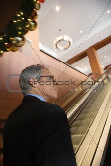 Businessman standing on escalator.