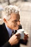 Businessman drinking coffee and smiling.