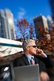 Businessman sitting  outside talking on cellphone with buildings
