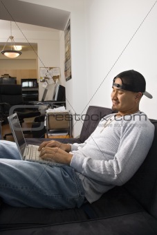Man sitting on sofa using laptop.