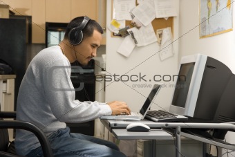 Man sitting at desk with computers.