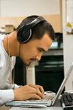 Man wearing headphones using laptop.