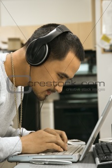 Man wearing headphones using laptop.