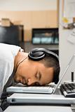 Man with headphones sleeping on laptop.