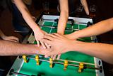 Hands together over foosball table.