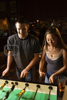 Young couple playing foosball table.