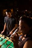 Young female drinking beer at foosball table.