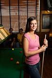 Young woman holding pool stick.