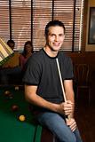 Young man holding pool stick.