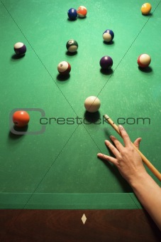 Female hand preparing to hit pool ball.