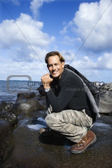 Man kneeling by the coast of Maui, Hawaii.