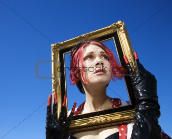 Adult female holding empty frame around face.