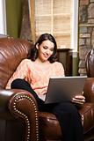 Woman sitting in chair with laptop.