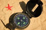 Compass and red star on sand