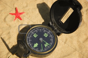Compass and red star on sand