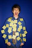 Caucasian teen boy covered with sticky notes screaming.