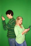 Caucasian teen boy and girl on cellphones.