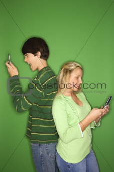 Caucasian teen boy and girl on cellphones.