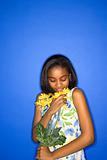 African-American teen girl smelling daisies.