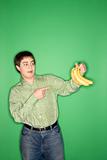 Caucasian teen boy pointing at bananas.