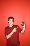Caucasian teen boy pointing to apple. 