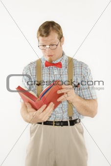 Young man dressed like nerd reading book.