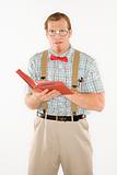 Young man dressed like nerd with book open.