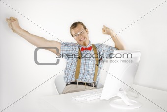 Young man stretching arms out at computer.