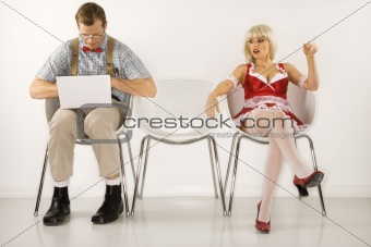 Young man sitting with laptop with young  woman looking at him.