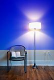 Lamp and chair with book against blue wall.