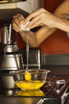 Young woman's hands cracking open an egg into a bowl.