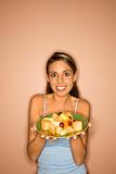 Young woman holding a plate of fruit.