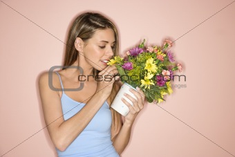 Mid-adult female smelling pot of flowers.