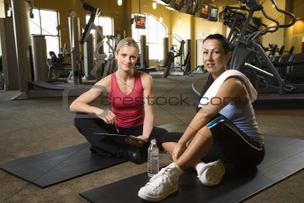Prime adult Caucasian female with personal trainer at gym.