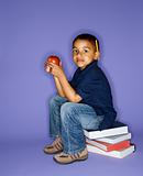 Boy sitting on stack of books.