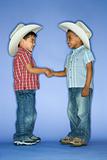 Boys in cowboy hats shaking hands.