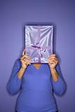 Woman holding present in front of face.
