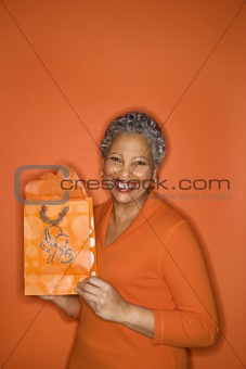 Woman holding gift bag smiling.