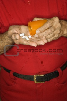 Man emptying pill bottle into hand.