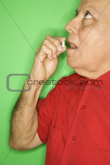 Man putting pill in mouth.