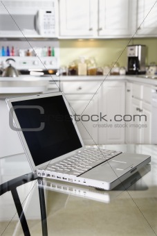 Open laptop computer on kitchen table.