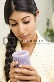 Young woman looking at lit candle.