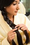Young woman braiding hair.