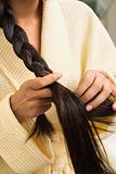 Young woman braiding hair.