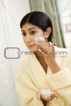 Young woman applying facial scrub.