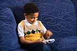 Young boy playing video game on couch. 