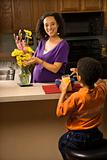 Pregnant mom arranging flowers while son eats breakfast. 