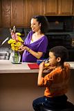 Pregnant mom arranging flowers while son eats breakfast. 
