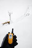 Gloved hand holding walkie talkie in snow scene.