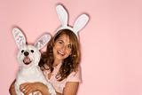 Woman and white dog wearing rabbit ears.